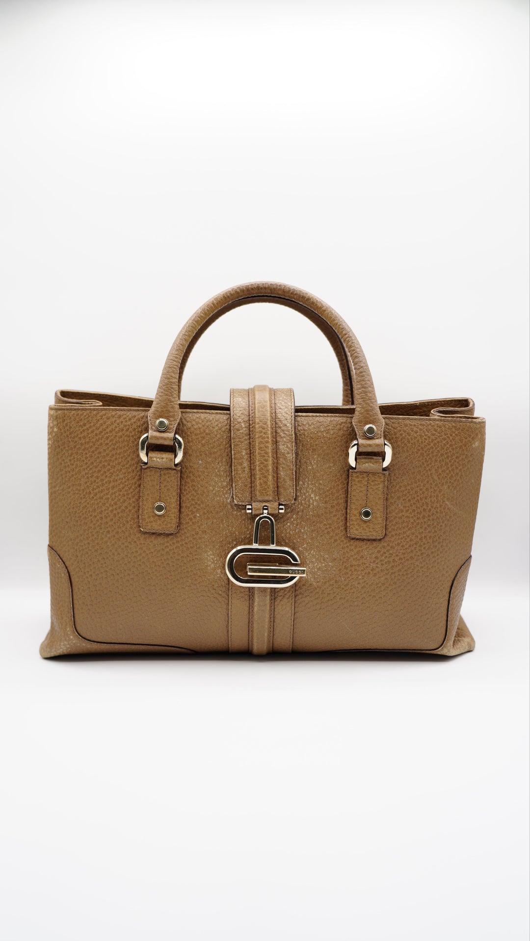 Brown leather handbag with gold hardware on a white background